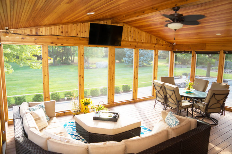 A sunroom with a wooden roof and ample seating.