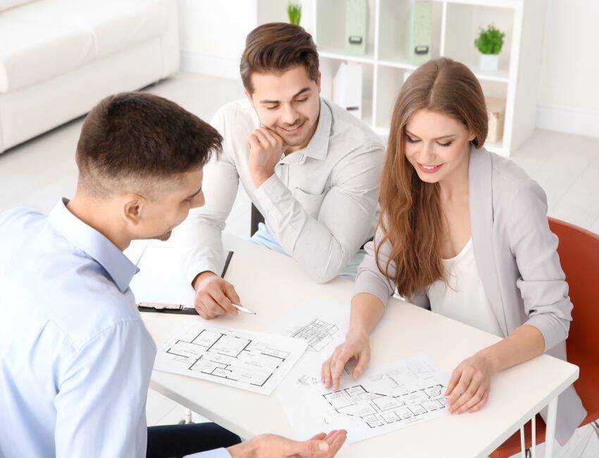 Home construction agent showing plan of apartment to clients in office