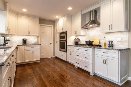 A white kitchen with wooden flooring.