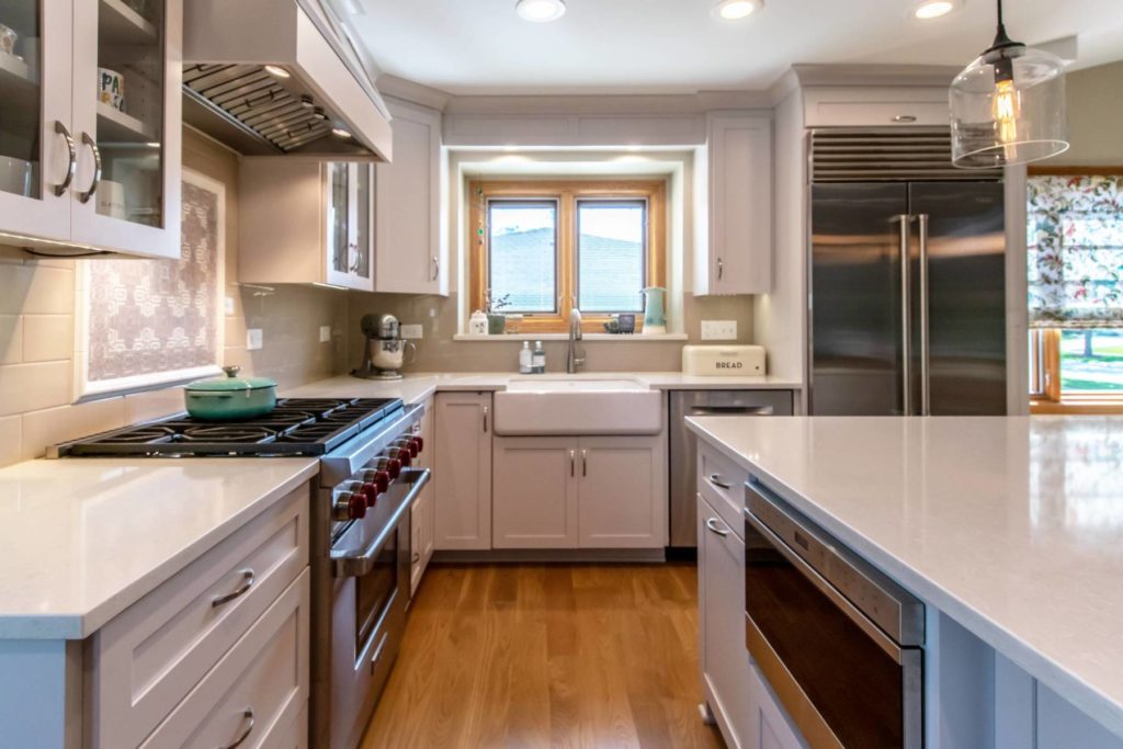 A newly remodeled kitchen with white cabinets, view facing the sink and window.